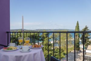 un tavolo con bicchieri da cibo e vino su un balcone di Hotel Adriatic a Biograd na Moru