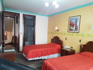 um quarto de hotel com duas camas com lençóis vermelhos em Paola Hostal em Sucre