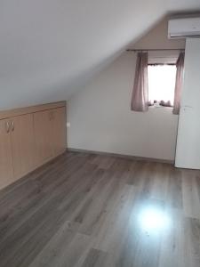 een lege witte kamer met een raam en houten vloeren bij Nefelejcs Nyaraló-Vendégház in Dunasziget