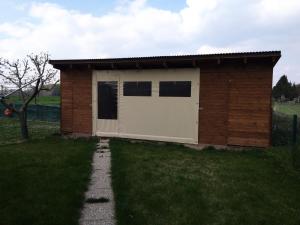 een klein gebouw met een witte deur in het gras bij Nefelejcs Nyaraló-Vendégház in Dunasziget