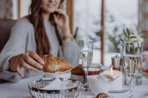 a woman sitting at a table talking on a cell phone at Hotel Berghof - St Johann in Salzburg in Sankt Johann im Pongau