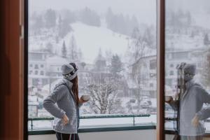 a woman standing in front of a window looking out at Hotel Berghof - St Johann in Salzburg in Sankt Johann im Pongau