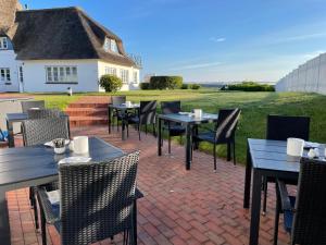 eine Terrasse mit Tischen und Stühlen auf einer Backsteinterrasse in der Unterkunft Haus Amanda in Norddorf