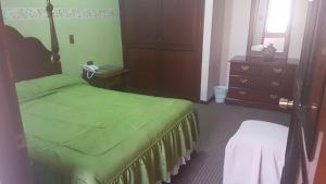 um quarto com uma cama verde e uma cómoda em Paola Hostal em Sucre