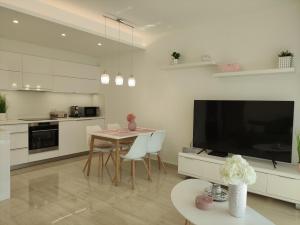 a kitchen with a table and a large screen television at Spa Residence Carbona EmDoNa Luxury Apartment in Hévíz