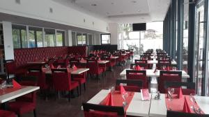 a dining room filled with tables and red chairs at Mátyás Apartmanház in Gyula