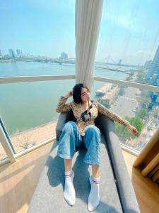 una mujer sentada en una silla en una ventana en Pariat River Front Hotel, en Da Nang