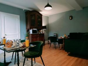 a living room with a table and green chairs at Clos Terre-lune in Nuits-Saint-Georges