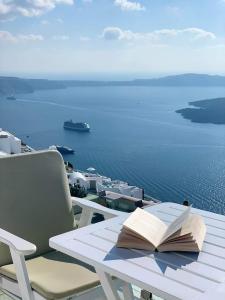 an open book on a table with a view of the ocean at Iliovasilema Hotel & Suites in Imerovigli