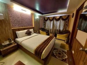 - une chambre avec un grand lit et des chaises dans l'établissement Astoria Residency, à Ooty