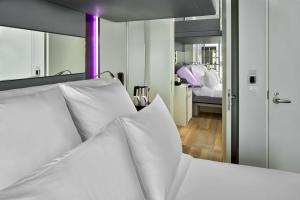 una camera da letto con un letto bianco e un grande specchio di YOTEL Singapore Orchard Road a Singapore