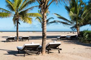 een strand met ligstoelen en palmbomen bij Ocean Beach Resort & SPA in Malindi