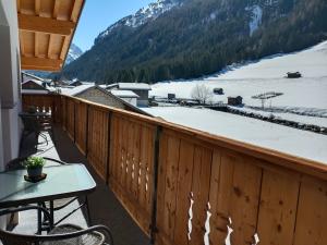 balcone con tavolo e montagna innevata di Apart Bergglück a Sankt Leonhard im Pitztal