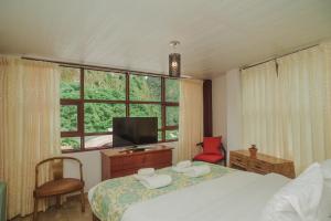 - une chambre avec un lit, une télévision et une fenêtre dans l'établissement Rupa Rupa High Jungle Eco B&B, à Machu Picchu