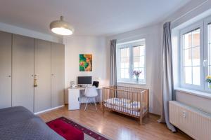 ein Schlafzimmer mit einem Kinderbett, einem Schreibtisch und Fenstern in der Unterkunft Apartment CHOPIN in Marienbad