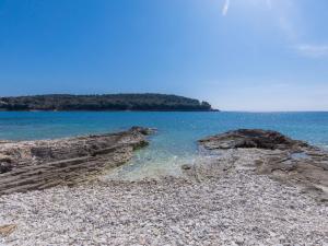 une plage avec des rochers et l'eau et une île dans l'établissement Apartment Joy by Interhome, à Pula