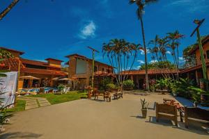 un patio con mesas, sillas y palmeras en Giprita Wellness Hotel Ubatuba, en Ubatuba