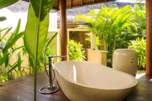 a bath tub sitting on a wooden deck with plants at Chanteak Bali in Jimbaran