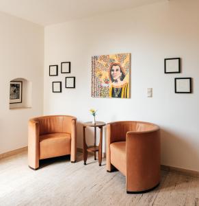 twee stoelen en een tafel in een kamer met een schilderij bij Hotel Markgraf in Klosterneuburg