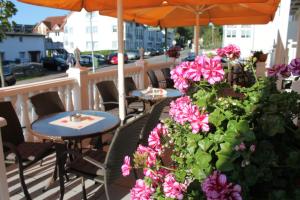 un patio con tavoli, sedie e fiori rosa di Hotel Selliner Hof a Ostseebad Sellin