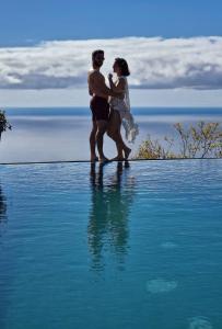 Ein Mann und eine Frau stehen im Wasser in der Unterkunft Madeira Sunset Cottage - Nature Retreat in Ponta do Pargo