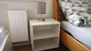 a white nightstand with a lamp on it next to a bed at Apartment am Südpark in Merseburg