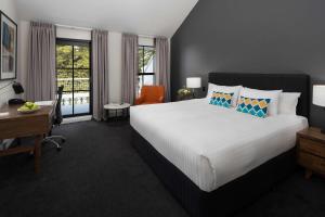 a bedroom with a large bed and a desk and window at Esplanade Hotel Fremantle - by Rydges in Fremantle