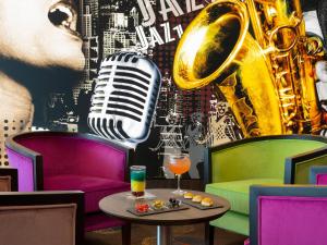 un bar con saxofón, una bebida y una mesa en Hôtel Roi Soleil Prestige Plaisir - St Quentin, en Plaisir