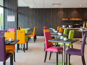 un comedor con sillas y mesas coloridas en Hôtel Roi Soleil Prestige Plaisir - St Quentin, en Plaisir