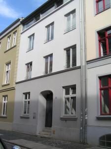 una vista esterna di un edificio bianco con finestre rosse di Ferienwohnungen Langenstraße - Altstadt a Stralsund