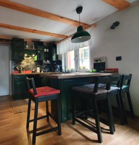 a kitchen with a green island with bar stools at Apartamenty Magiczna Wenecja in Cieszyn