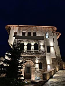 Un grand bâtiment avec des lumières allumées la nuit dans l'établissement KERCULLA Resort, à Gjirokastër