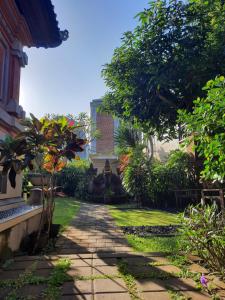 un jardín con una pasarela de piedra frente a un edificio en Sahadewa House, en Ubud