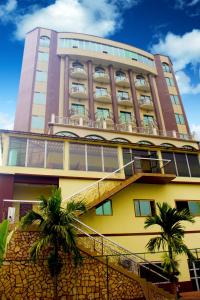 un edificio alto con palmeras delante en FELICIA HOTEL YAOUNDE, en Yaoundé