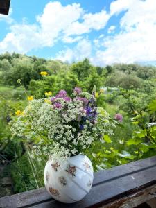 a white vase filled with flowers sitting on a bench at Livada lui Papu in Izvoarele