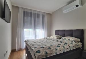 um quarto com uma cama e uma janela em Green Apartments Podgorica With Garage em Podgorica