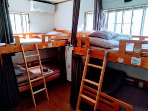 een slaapkamer met 2 stapelbedden en 2 stoelen bij Osaka Tomato Guesthouse in Osaka