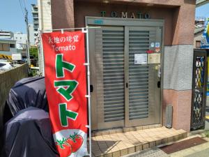 een voordeur van een gebouw met een bord erop bij Osaka Tomato Guesthouse in Osaka