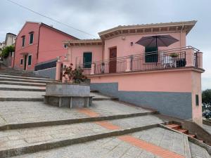 um edifício cor-de-rosa com uma varanda com um guarda-chuva em Diaboliko Apartment em Capoliveri