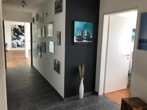 a hallway with a white vase on a wall with pictures at Gästezimmer Erlinsbach bei Aarau, zwischen Aare und Jura in Niedererlinsbach