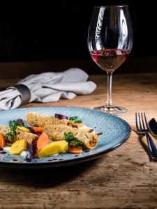 a blue plate of food and a glass of wine at Hotel Löwenhof in Bressanone