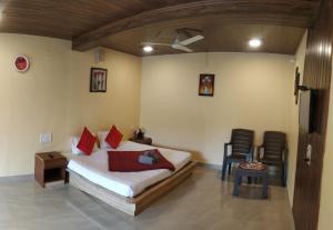 1 dormitorio con 1 cama, mesa y sillas en Bluebell Residency, en Mahabaleshwar