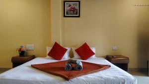 Habitación de hotel con cama con almohadas rojas en Bluebell Residency, en Mahabaleshwar