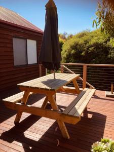 een houten picknicktafel met een paraplu en een picknick bij Red ceder cottage - Great ocean road - Port Campbell in Port Campbell