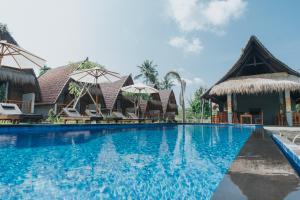 uma piscina num resort com cadeiras e guarda-sóis em Sundi Hill Cottage em Nusa Penida