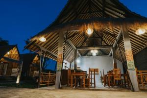 um pavilhão com cadeiras e mesas de madeira em Sundi Hill Cottage em Nusa Penida