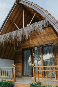 uma casa com um telhado de palha e um alpendre em Sundi Hill Cottage em Nusa Penida