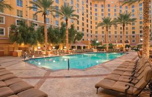 uma piscina num hotel com cadeiras e palmeiras em Club Wyndham Grand Desert em Las Vegas