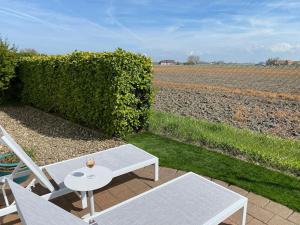 eine Terrasse mit einem Tisch, 2 Stühlen und einem Feld in der Unterkunft Charlie & Chloé’s beachcondo ***** in De Haan