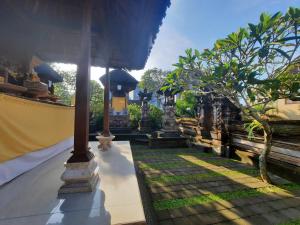 un patio de una casa con un árbol y un edificio en Sahadewa House, en Ubud